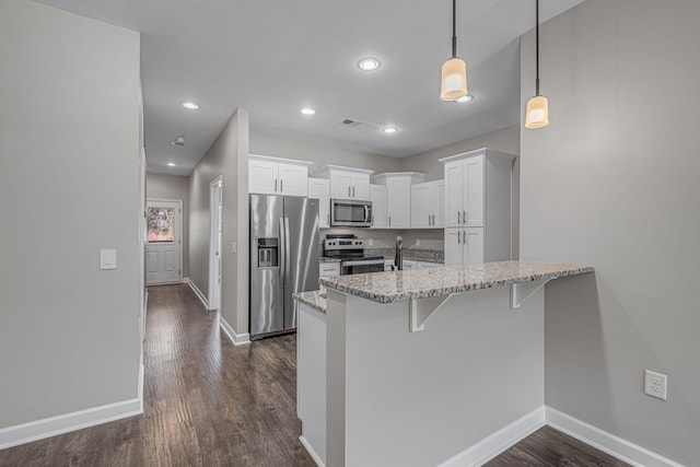 kitchen featuring white cabinets, light stone counters, a breakfast bar, a peninsula, and stainless steel appliances