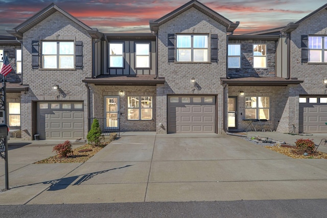 view of property featuring a garage, brick siding, and driveway