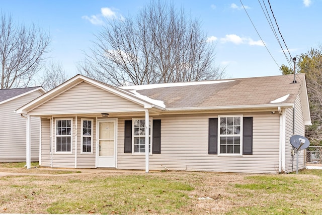 ranch-style home featuring a front lawn and roof with shingles