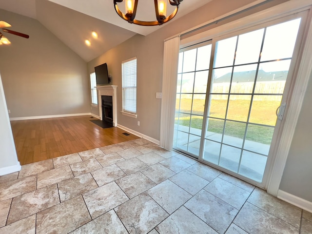 unfurnished living room with lofted ceiling, a fireplace with flush hearth, visible vents, and baseboards