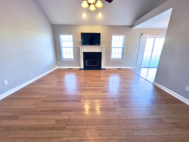 unfurnished living room with plenty of natural light, vaulted ceiling, and wood finished floors