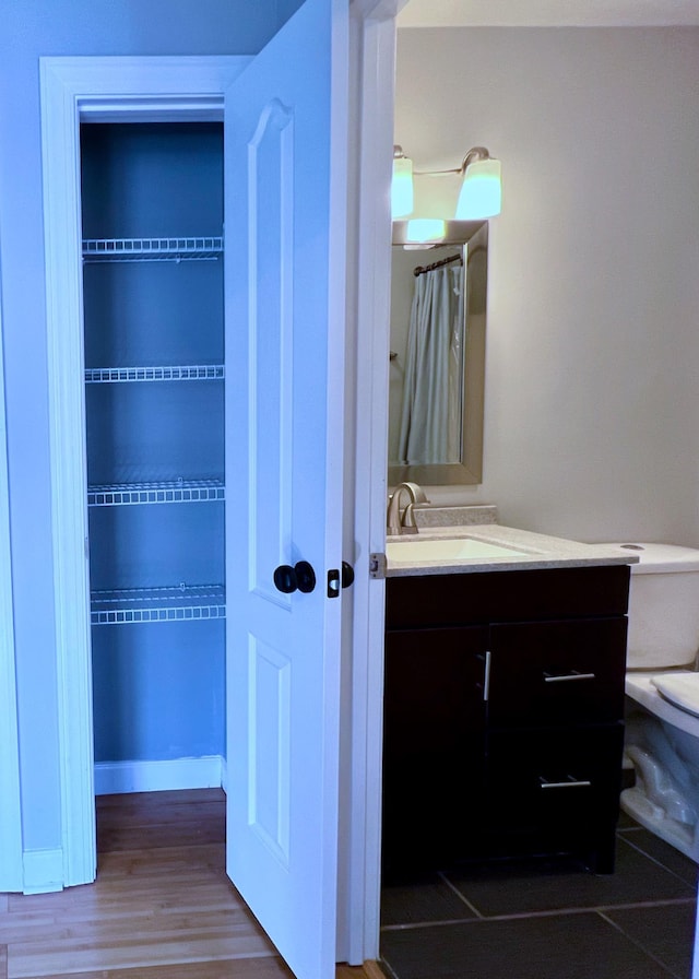 bathroom with baseboards, vanity, toilet, and wood finished floors