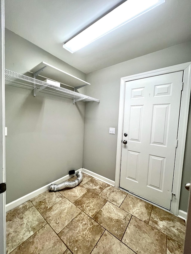 washroom with stone tile floors and baseboards