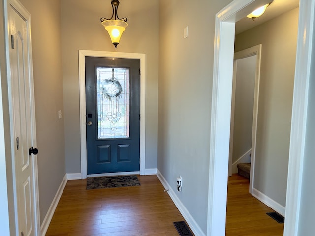 foyer entrance with baseboards, visible vents, and wood finished floors