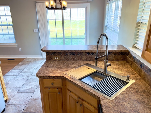 kitchen featuring plenty of natural light, dark countertops, decorative light fixtures, and a sink