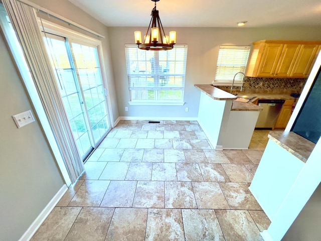 kitchen featuring baseboards, dishwasher, decorative light fixtures, a sink, and backsplash