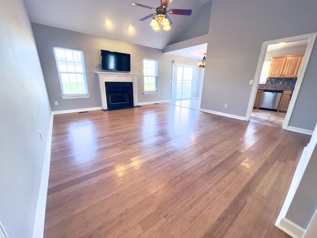 unfurnished living room with a fireplace, a ceiling fan, baseboards, vaulted ceiling, and light wood-type flooring