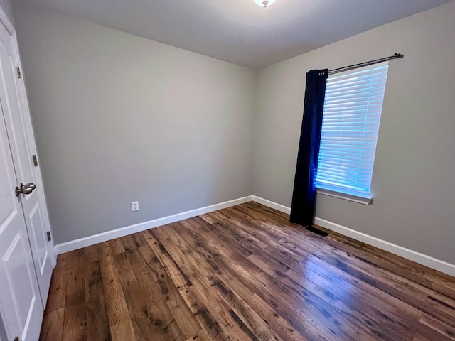 spare room with dark wood-style flooring and baseboards