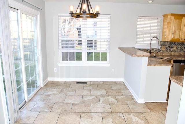 unfurnished dining area with a notable chandelier, visible vents, baseboards, and a sink