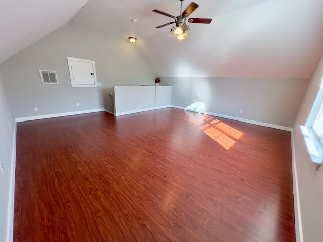 additional living space featuring dark wood-type flooring, lofted ceiling, visible vents, and baseboards