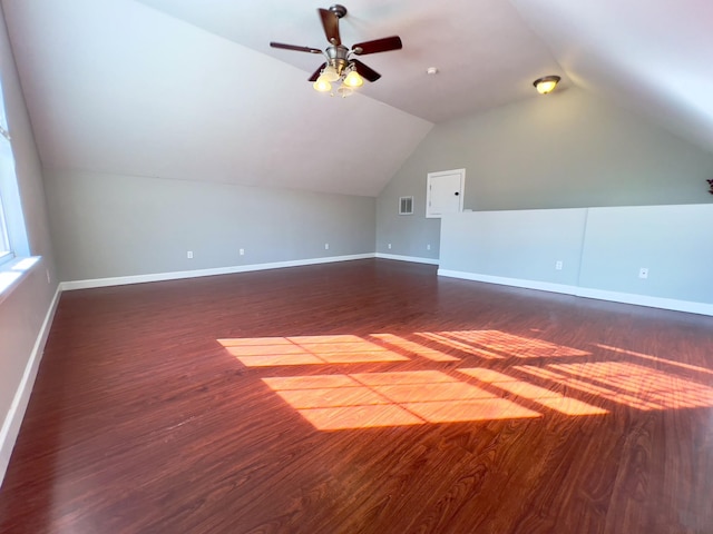 additional living space with dark wood-style flooring, visible vents, vaulted ceiling, and baseboards