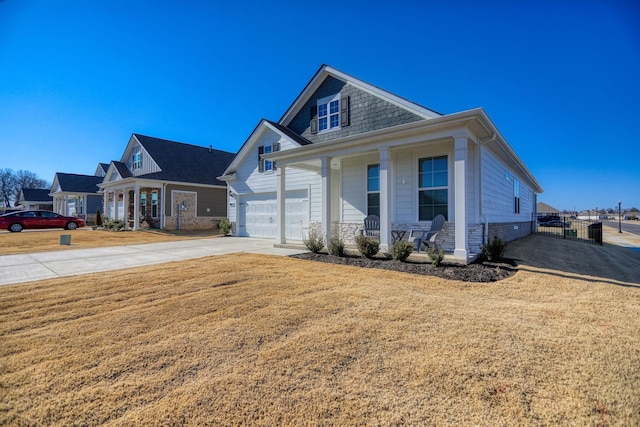 view of front of house featuring a porch, concrete driveway, fence, a garage, and stone siding