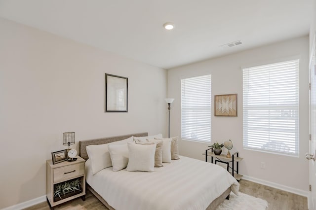 bedroom featuring baseboards, visible vents, and wood finished floors