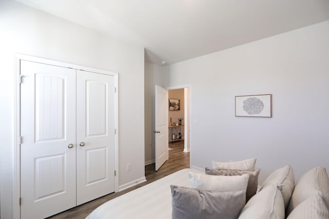 bedroom with dark wood-type flooring, a closet, and baseboards