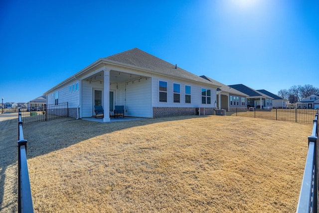 rear view of property with brick siding, a patio area, a fenced backyard, and a residential view