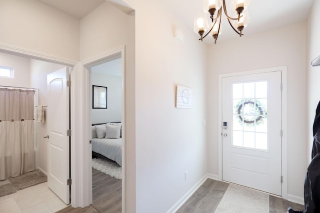 foyer entrance featuring light wood-style floors, baseboards, and a chandelier