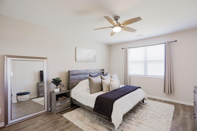 bedroom featuring ceiling fan, wood finished floors, visible vents, and baseboards