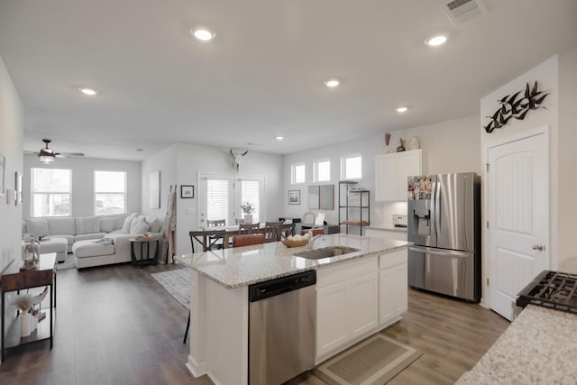 kitchen with a center island with sink, white cabinetry, stainless steel appliances, and open floor plan