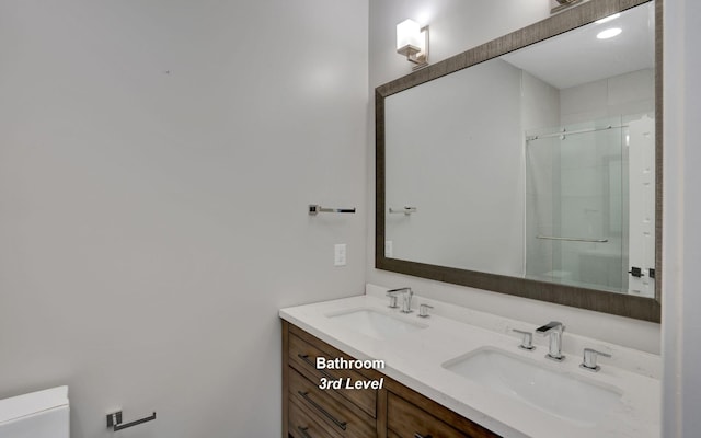 bathroom featuring double vanity, a stall shower, a sink, and toilet