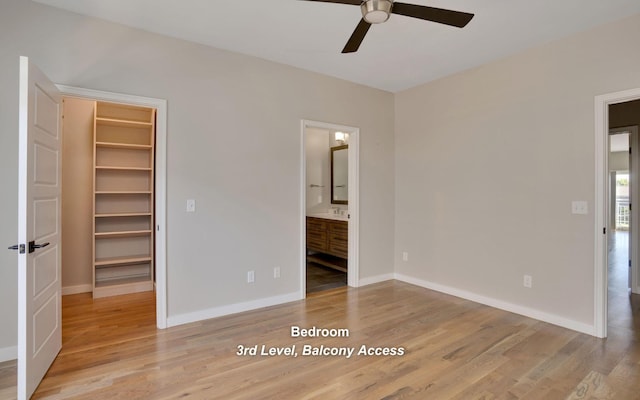 unfurnished bedroom with light wood-type flooring, baseboards, and a walk in closet