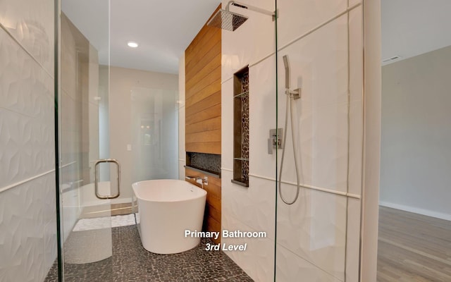 bathroom with a stall shower, a freestanding bath, and recessed lighting