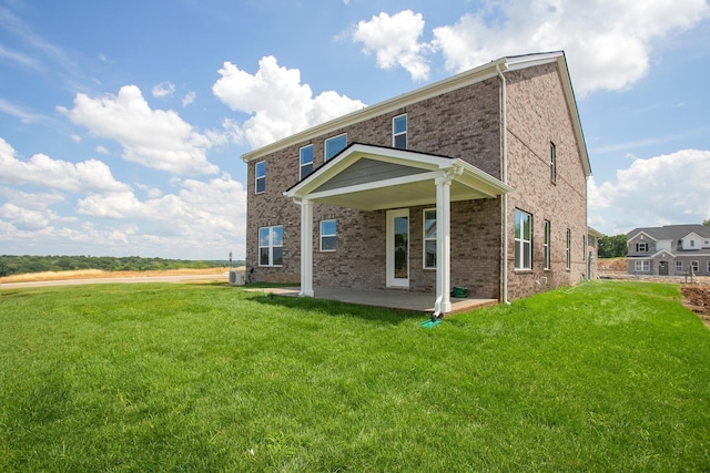 back of house featuring a yard, brick siding, and a patio area