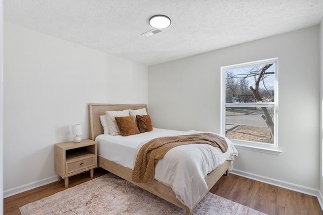 bedroom with multiple windows, wood finished floors, and baseboards