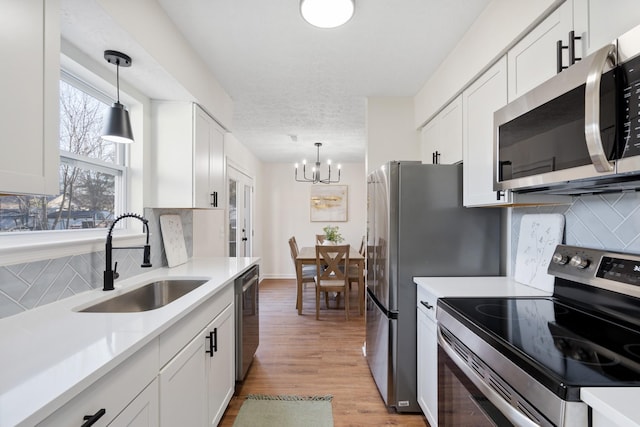 kitchen featuring a sink, stainless steel appliances, light countertops, and white cabinetry