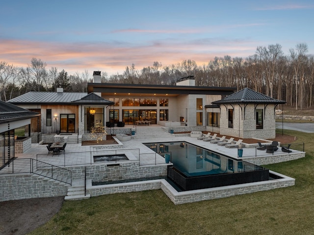 rear view of property featuring an outdoor pool, a chimney, metal roof, a standing seam roof, and a patio area