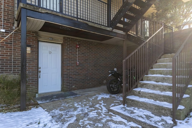 snow covered property entrance with brick siding