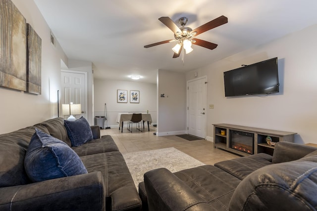 living room with light tile patterned floors, ceiling fan, and baseboards