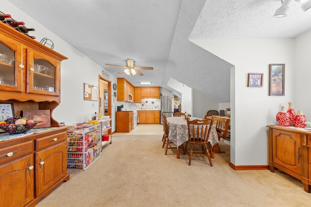 dining space with light colored carpet, ceiling fan, a textured ceiling, and baseboards