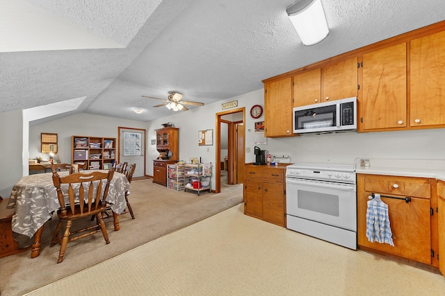 kitchen featuring white electric stove, light countertops, stainless steel microwave, light colored carpet, and brown cabinetry