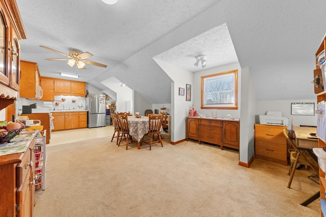 interior space featuring light colored carpet, light countertops, brown cabinetry, freestanding refrigerator, and a sink