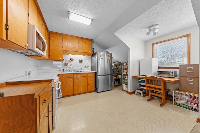 kitchen featuring light countertops, white appliances, a sink, and brown cabinets