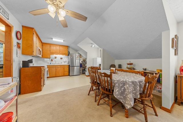 dining area featuring lofted ceiling, ceiling fan, a textured ceiling, and light carpet