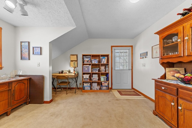 interior space featuring light colored carpet, a textured ceiling, and baseboards