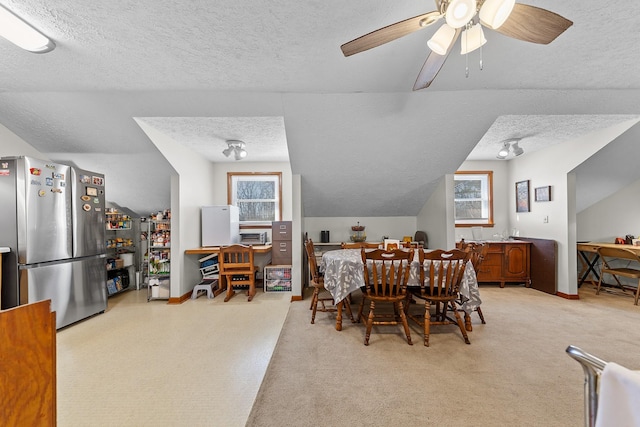 dining room with a textured ceiling, vaulted ceiling, plenty of natural light, and baseboards