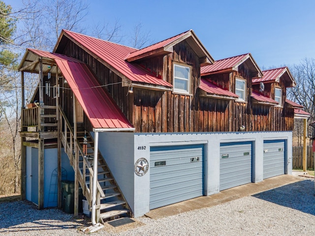 view of front of home with a garage, metal roof, and stairs