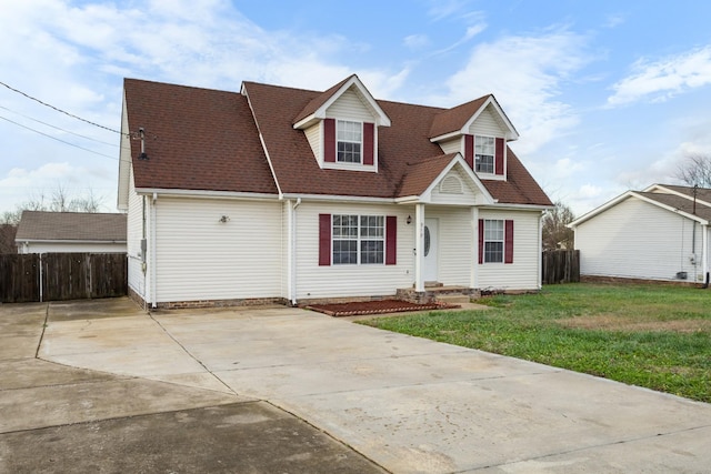 cape cod-style house with concrete driveway, a front lawn, a shingled roof, and fence