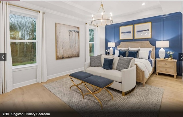 bedroom featuring a tray ceiling, multiple windows, and light wood-style flooring