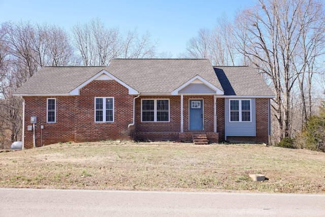 ranch-style home featuring a shingled roof, a front yard, and brick siding