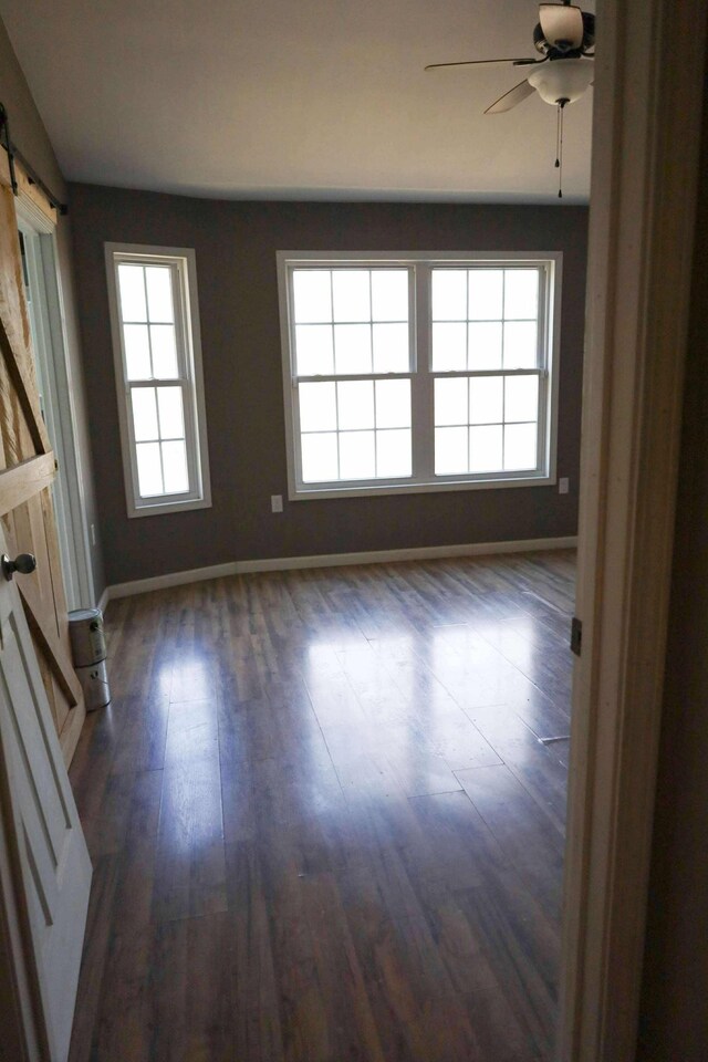 1335 Bumpus Mills Rd, Dover, TN 37058 - spare room with a barn door, baseboards, dark wood-style flooring, and ceiling fan