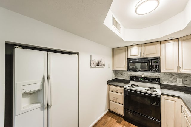 kitchen with white refrigerator with ice dispenser, visible vents, electric range oven, dark countertops, and black microwave