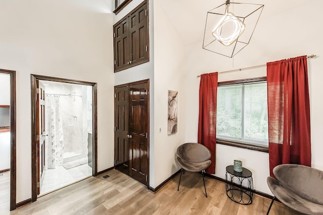 entrance foyer with a towering ceiling, light wood-style flooring, and baseboards