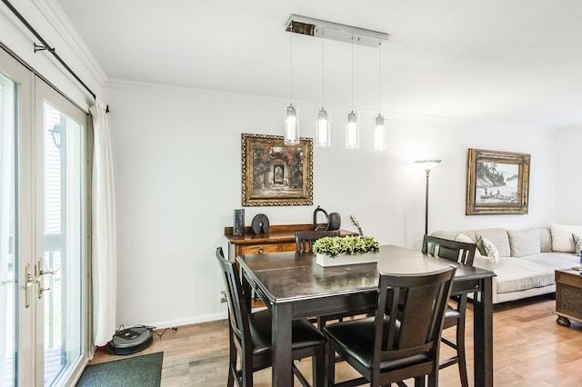 dining space with light wood-style floors, baseboards, and ornamental molding