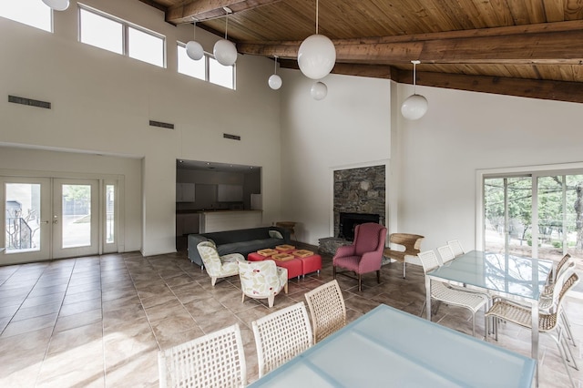 tiled living room featuring wooden ceiling, a fireplace, visible vents, french doors, and beamed ceiling