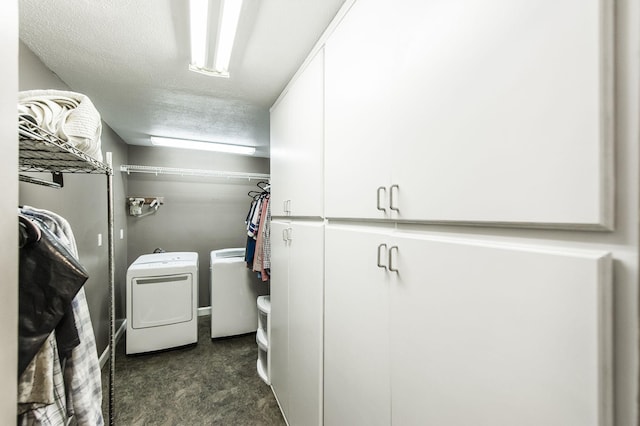 washroom featuring a textured ceiling, separate washer and dryer, and cabinet space