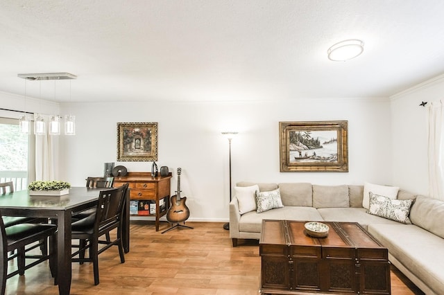 living area with crown molding, baseboards, visible vents, and light wood-style floors