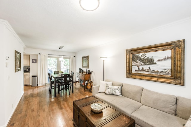 living area featuring ornamental molding, baseboards, and wood finished floors